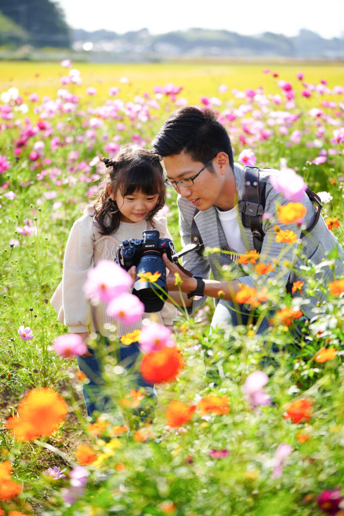 千葉の出張撮影「ジョイスタジオ（Joystudio）」が、花畑のロケーションで子どもと笑顔でコミュニケーションを取りながら自然な表情を引き出している撮影風景